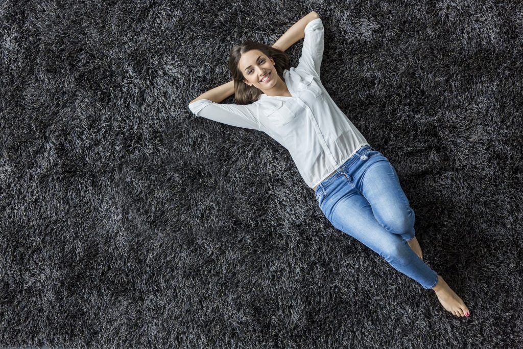 Southern Flooring Company young woman laying on a carpet at home shot from overhead